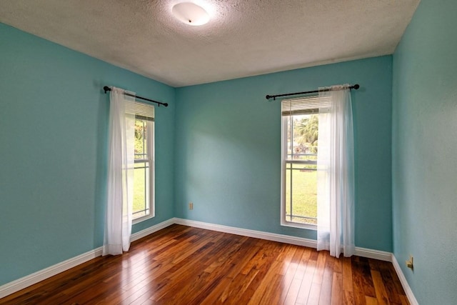 empty room with a textured ceiling and dark wood-type flooring