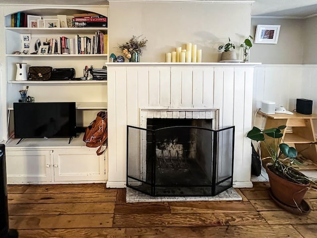 room details with wood-type flooring, ornamental molding, and a brick fireplace