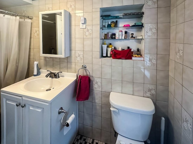 bathroom with vanity, toilet, and tile walls