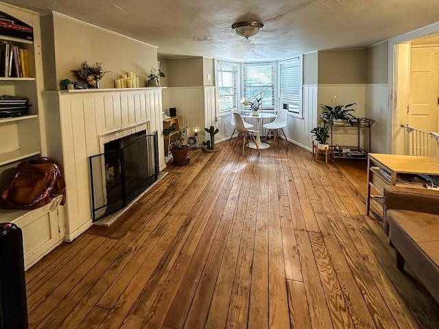 sitting room featuring wood-type flooring, a textured ceiling, and built in features