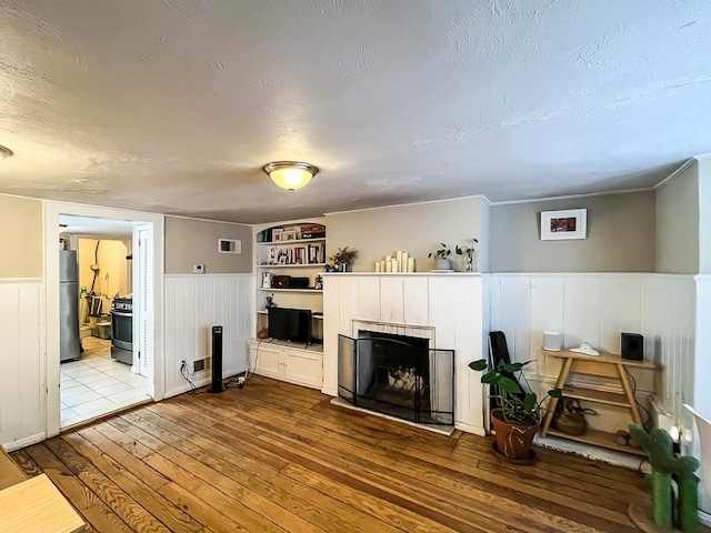 living room with hardwood / wood-style flooring, built in shelves, and a textured ceiling