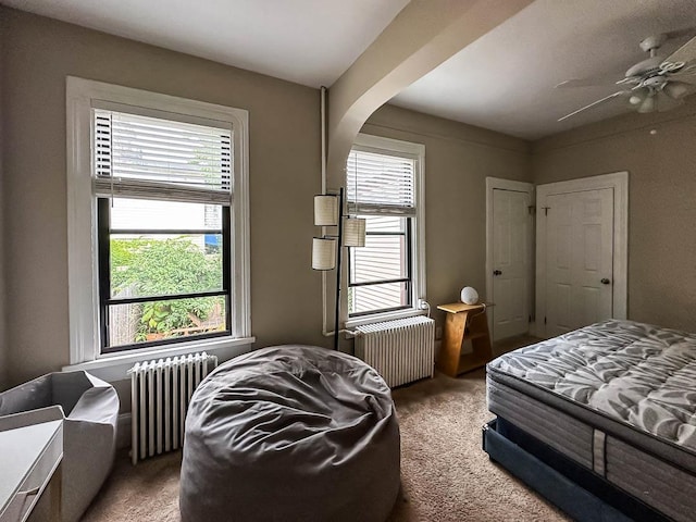 carpeted bedroom with ceiling fan and radiator heating unit