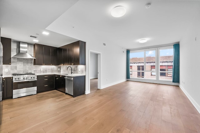 kitchen featuring decorative backsplash, wall chimney exhaust hood, stainless steel appliances, sink, and light hardwood / wood-style flooring