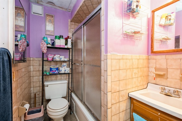 73 Laidlaw Ave, Jersey City, NJ 07306 - full bathroom with tile walls, toilet, vanity, a wainscoted wall, and bath / shower combo with glass door