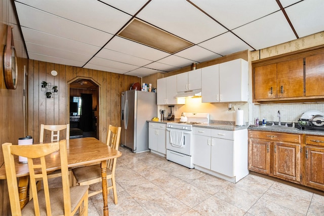 73 Laidlaw Ave, Jersey City, NJ 07306 - kitchen with white range with gas stovetop, stainless steel fridge with ice dispenser, a sink, under cabinet range hood, and wood walls