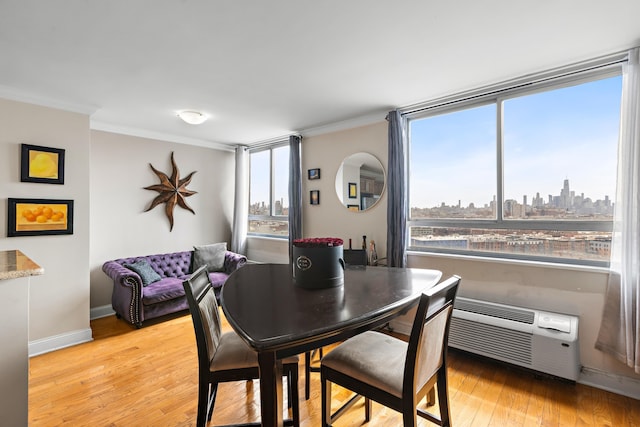 dining area featuring ornamental molding, light wood-style floors, baseboards, a skyline view, and a wall mounted AC