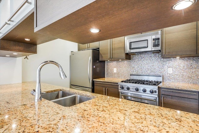 kitchen featuring dark brown cabinetry, decorative backsplash, appliances with stainless steel finishes, and a sink