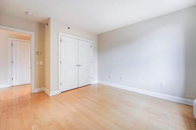 unfurnished bedroom with a closet, baseboards, and light wood finished floors