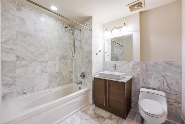 full bathroom with visible vents, marble finish floor, tile walls, bathing tub / shower combination, and vanity