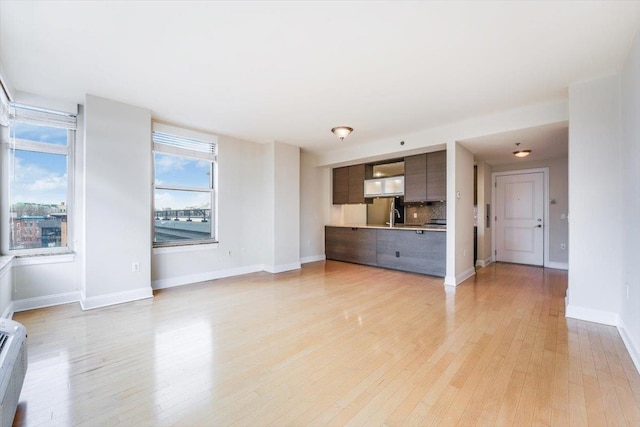 unfurnished living room with baseboards and light wood-style flooring