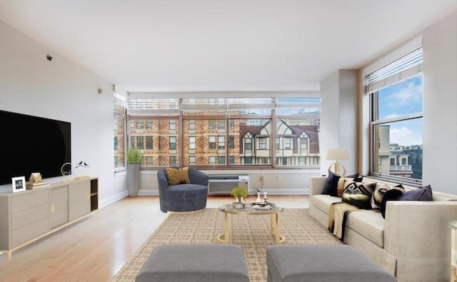 living area with an AC wall unit, baseboards, and wood finished floors