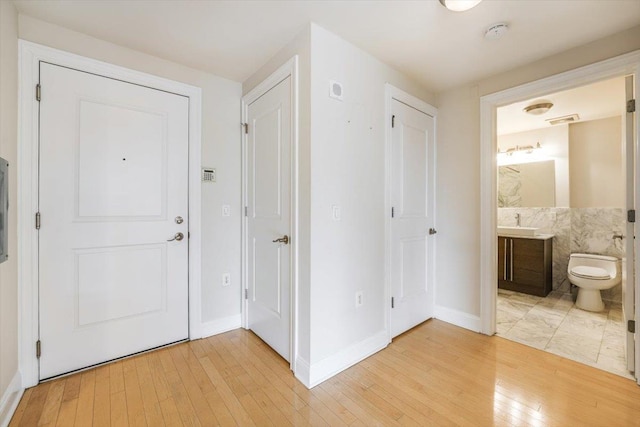 foyer with light wood-style floors, visible vents, and baseboards