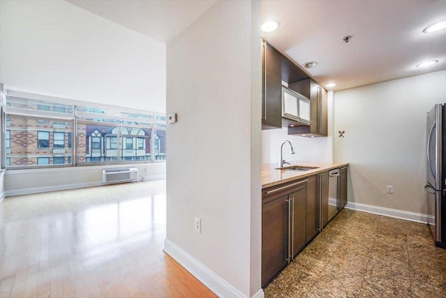 kitchen with dark brown cabinets, baseboards, appliances with stainless steel finishes, and a sink