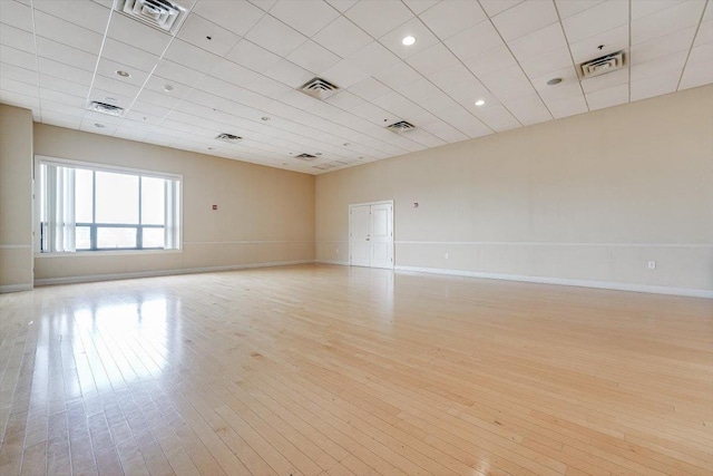 empty room featuring light wood-style floors, visible vents, and baseboards