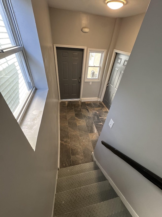 stairway featuring baseboards and stone finish flooring