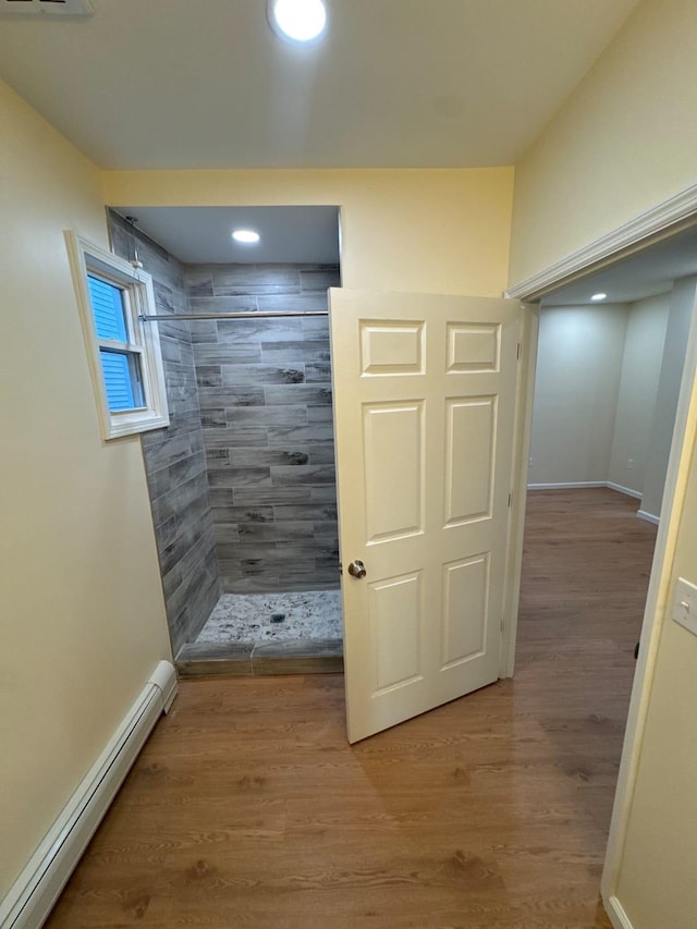 full bath with a tile shower, recessed lighting, baseboard heating, wood finished floors, and baseboards