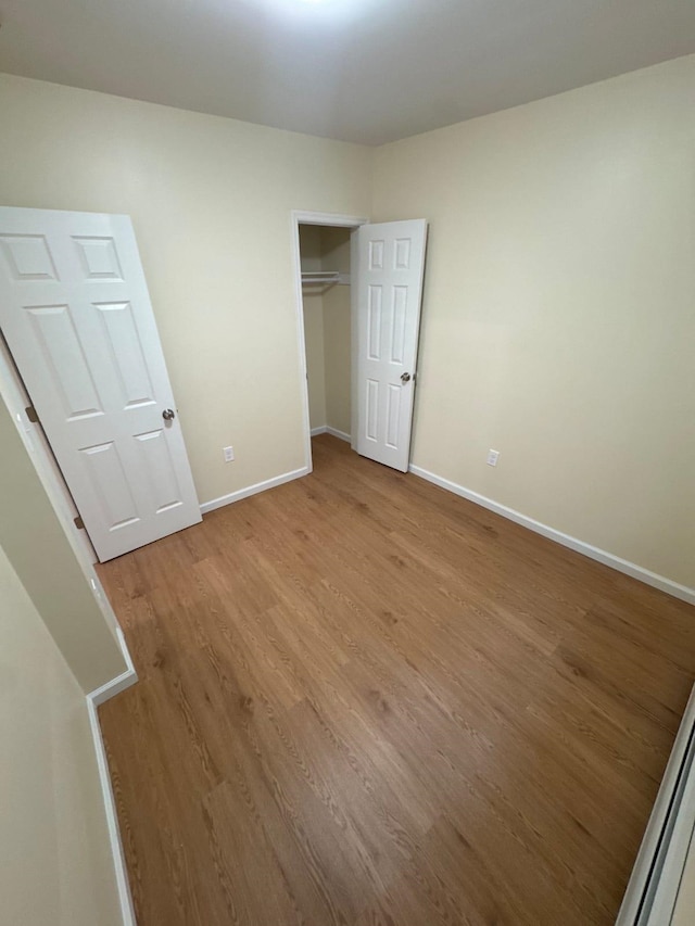 unfurnished bedroom featuring light wood-type flooring, a closet, and baseboards