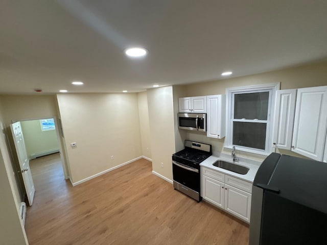 kitchen with stainless steel appliances, light wood-style floors, a baseboard heating unit, and a sink