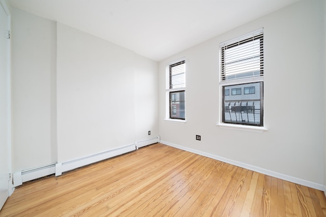 spare room with baseboards, baseboard heating, and hardwood / wood-style floors