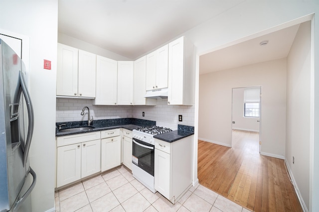 kitchen featuring a sink, backsplash, under cabinet range hood, stainless steel refrigerator with ice dispenser, and white range with gas cooktop