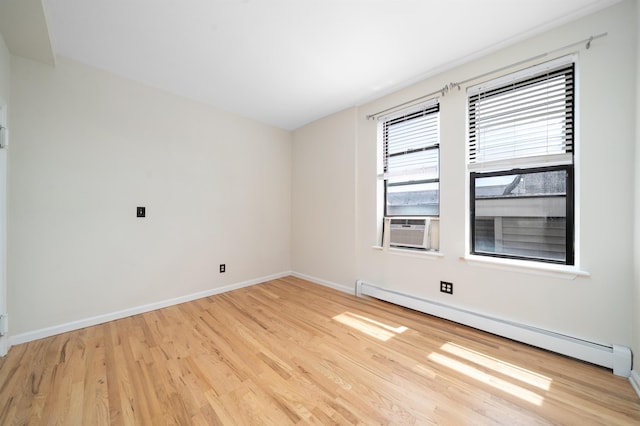 spare room featuring light wood-style floors, a baseboard radiator, baseboards, and cooling unit
