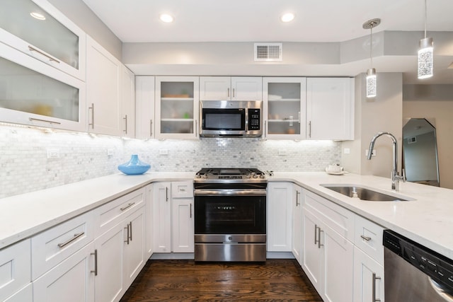 126 Delaware Ave Unit 10, Jersey City, NJ 07306 - kitchen featuring appliances with stainless steel finishes, a sink, dark wood-type flooring, white cabinetry, and hanging light fixtures