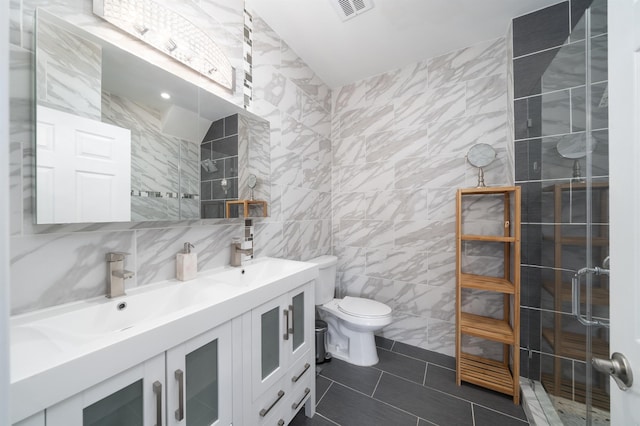 full bathroom with a tile shower, double vanity, toilet, and a sink