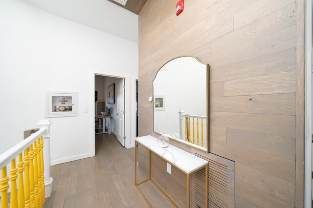 hallway featuring baseboards, an upstairs landing, and dark wood-style flooring