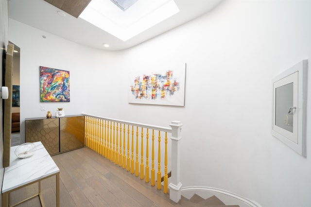 hall featuring a skylight, an upstairs landing, and wood finished floors