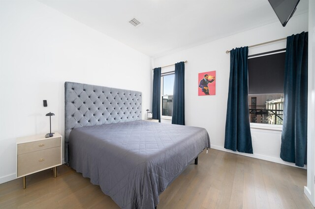 bedroom featuring visible vents, baseboards, and wood finished floors