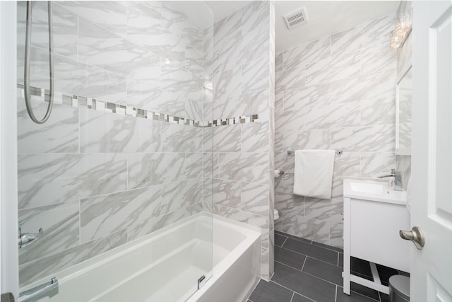 bathroom featuring visible vents, shower / washtub combination, vanity, tile patterned floors, and tile walls