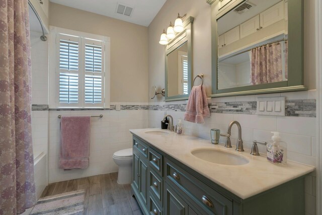 91 Sherman Pl, Jersey City, NJ 07307 - bathroom with wood finished floors, double vanity, toilet, shower / bath combination with curtain, and tile walls