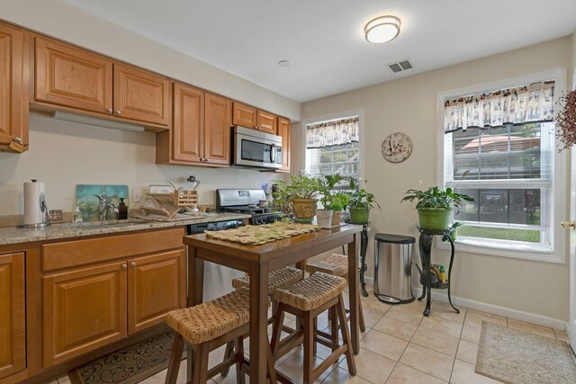91 Sherman Pl, Jersey City, NJ 07307 - kitchen featuring stainless steel appliances, brown cabinetry, light tile patterned floors, baseboards, and a sink