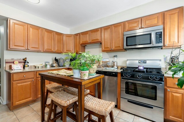 91 Sherman Pl, Jersey City, NJ 07307 - kitchen with appliances with stainless steel finishes, light tile patterned floors, and light stone countertops