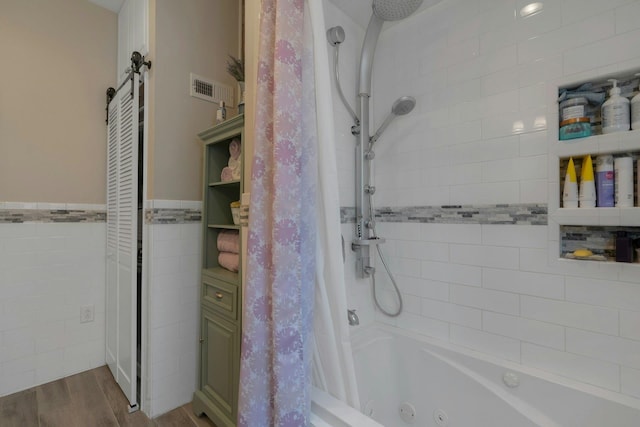 91 Sherman Pl, Jersey City, NJ 07307 - bathroom featuring a combined bath / shower with jetted tub, wood finished floors, tile walls, and wainscoting