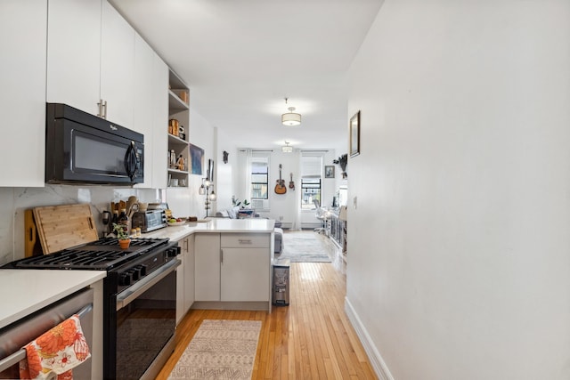60 Monroe St Unit 8, Hoboken, NJ 07030 - kitchen with black appliances, a peninsula, light wood-style flooring, white cabinetry, and open shelves