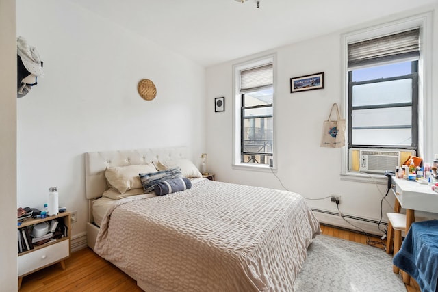 60 Monroe St Unit 8, Hoboken, NJ 07030 - bedroom featuring a baseboard radiator, multiple windows, wood finished floors, and cooling unit