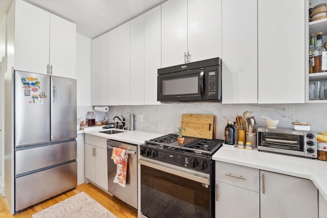 60 Monroe St Unit 8, Hoboken, NJ 07030 - kitchen featuring appliances with stainless steel finishes, light countertops, a sink, light wood finished floors, and white cabinets