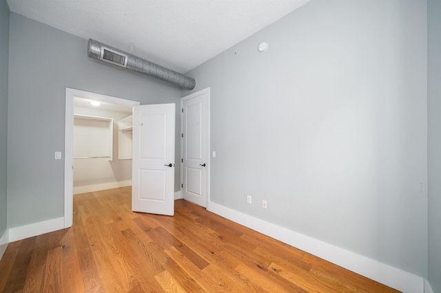 unfurnished bedroom with a closet, a walk in closet, and light hardwood / wood-style floors