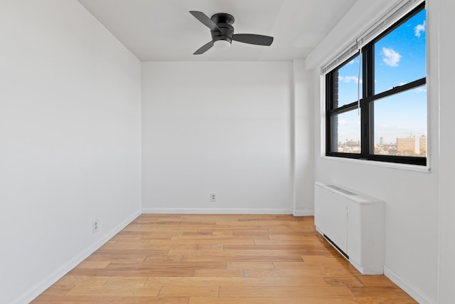 spare room featuring radiator, ceiling fan, and light wood-type flooring