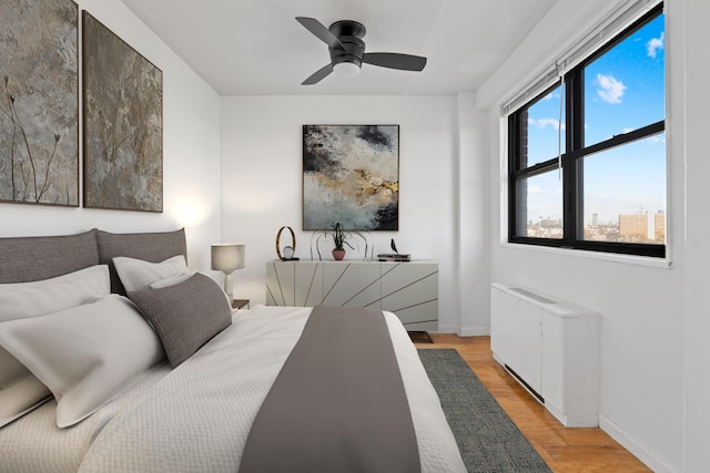 bedroom with ceiling fan, radiator heating unit, and light hardwood / wood-style flooring