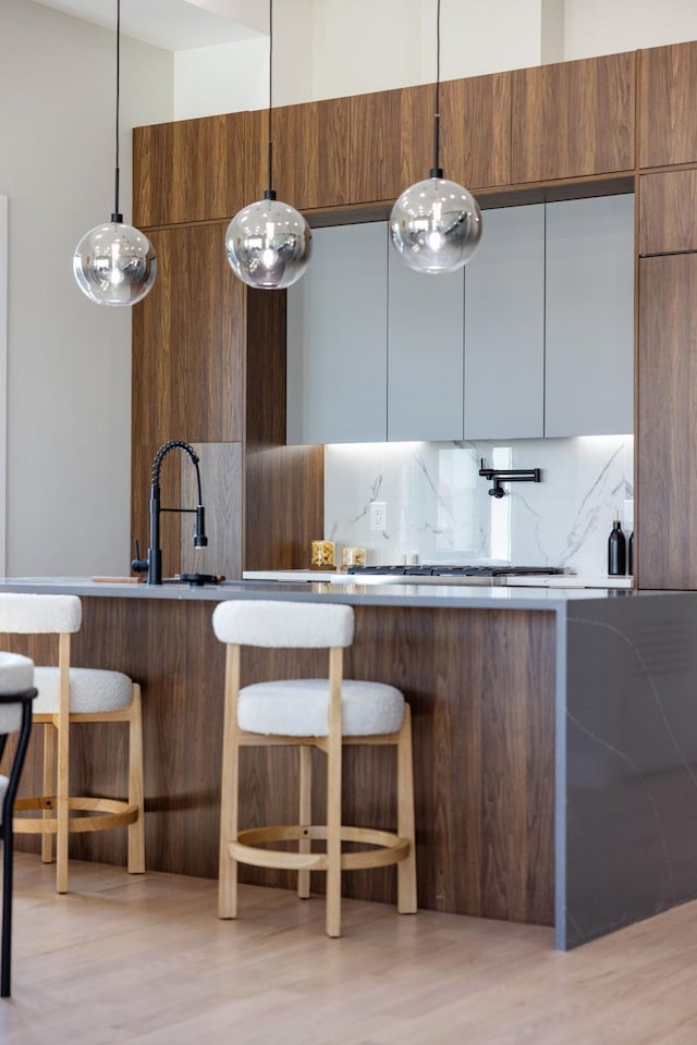 371 New York Ave Unit 2, Jersey City, NJ 07307 - kitchen featuring modern cabinets, tasteful backsplash, a breakfast bar area, a sink, and light wood-type flooring
