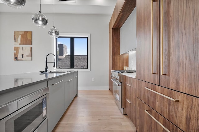 371 New York Ave Unit 2, Jersey City, NJ 07307 - kitchen with modern cabinets, stainless steel appliances, a sink, light wood finished floors, and decorative light fixtures