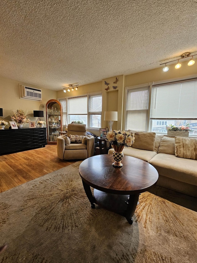 living room featuring rail lighting, wood-type flooring, and a textured ceiling