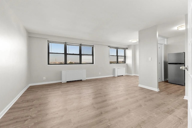 1225 Kennedy Blvd Unit 9H, Bayonne, NJ 07002 - unfurnished living room featuring radiator and light wood-style flooring