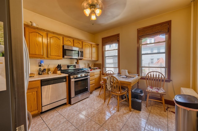 159 W 33rd St, Bayonne, NJ 07002 - kitchen featuring stainless steel appliances, light countertops, a ceiling fan, light tile patterned floors, and brown cabinetry