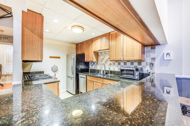 kitchen featuring visible vents, backsplash, appliances with stainless steel finishes, a sink, and dark stone counters