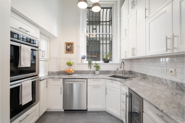 83 Montgomery St Unit 201, Jersey City, NJ 07302 - kitchen featuring appliances with stainless steel finishes, wine cooler, white cabinets, decorative backsplash, and light stone countertops
