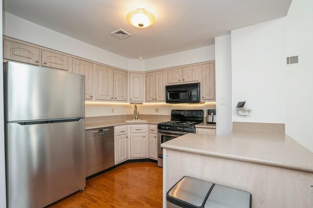 4313 Smith Ave Unit 10, North Bergen, NJ 07047 - kitchen featuring appliances with stainless steel finishes, a sink, a peninsula, light countertops, and wood finished floors
