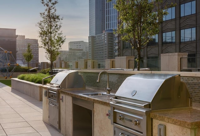 patio terrace at dusk with a grill, area for grilling, and sink